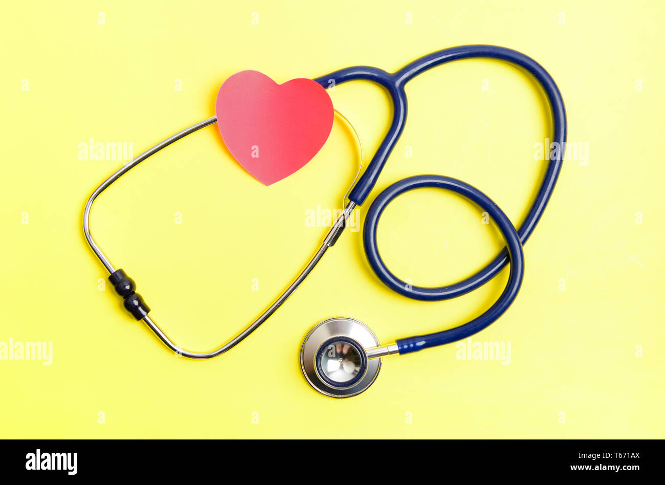 Stethoskop und rotes Herz Form Aufkleber auf gelben Hintergrund. Healthcare prüfen Konzept Stockfoto