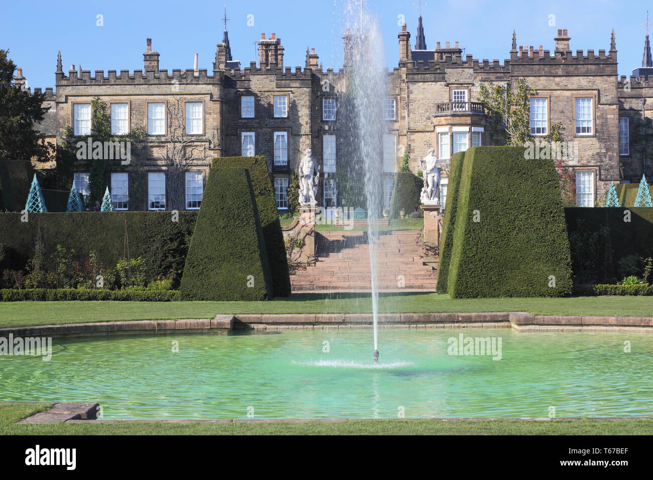 Renishaw Hall vom Pool durch Taxus Whipplei (Eibe) Formgehölze Absicherung im Frühjahr, Derbyshire, England, UK gesehen Stockfoto