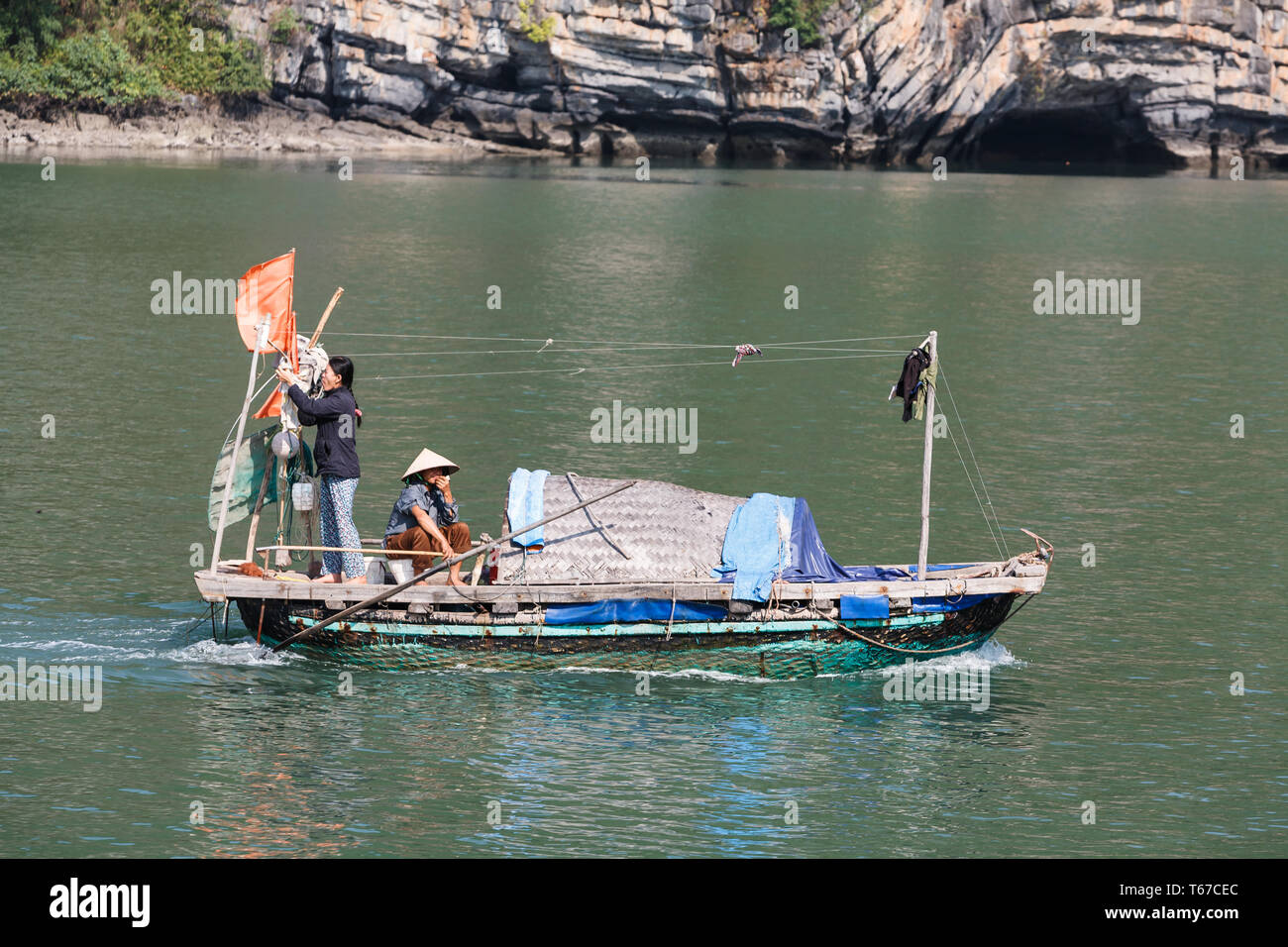 Traditionelle Familie Fischerboot mit Wäscheleine, Wäsche aufhängen und gebogene Hütte zum Schlafen durch die Halong Bay Vietnam mit zwei Personen Stockfoto
