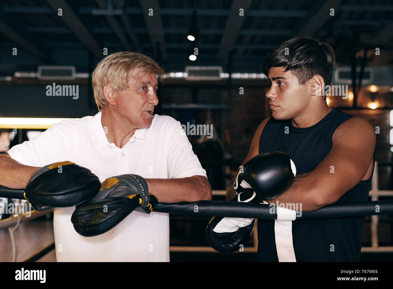 Junge boxer Hören seines reifen Trainer. Seitenansicht eines zwei Sport stehende Person in boxer Ring. Stockfoto