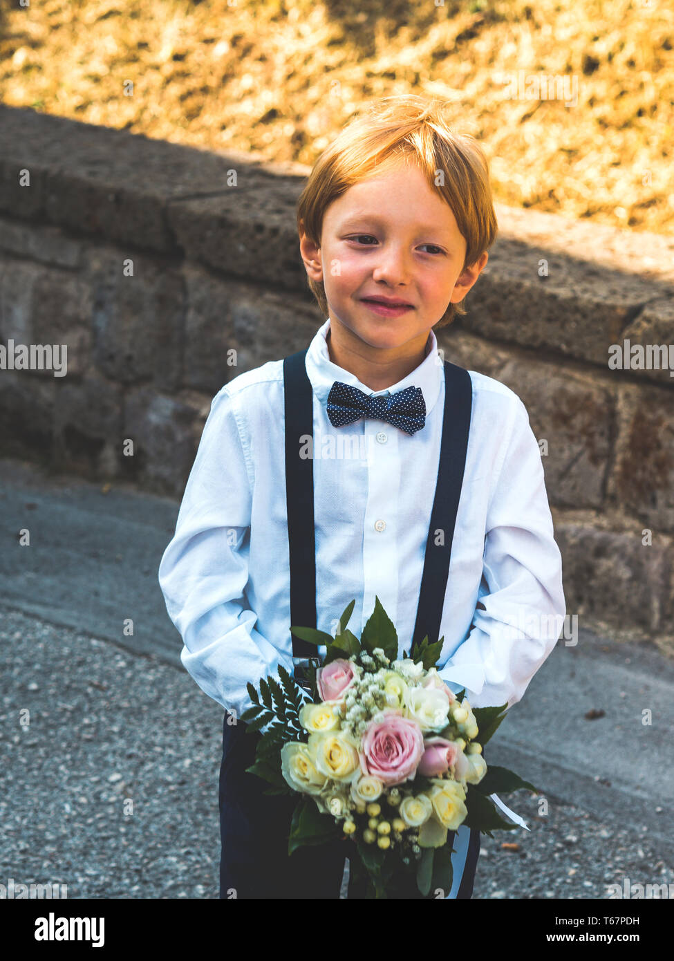 Kleinen Niedlichen ring Bearer in Garten Hochzeit spielen mit Blumenstrauß Stockfoto