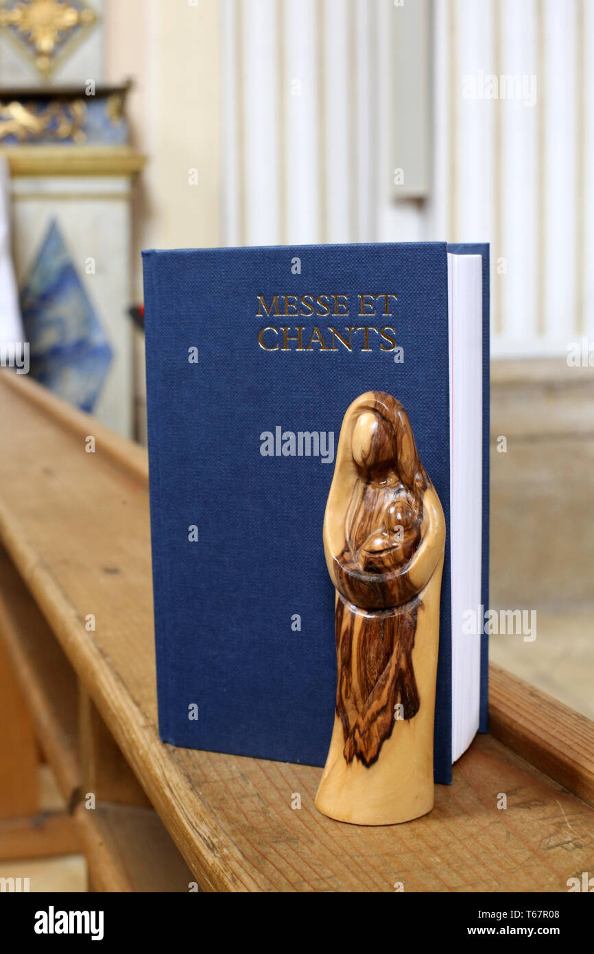 Statue de la Vierge à l'Enfant en bois d'Olivier et Livre de Messe et Chants dans une Église. Stockfoto