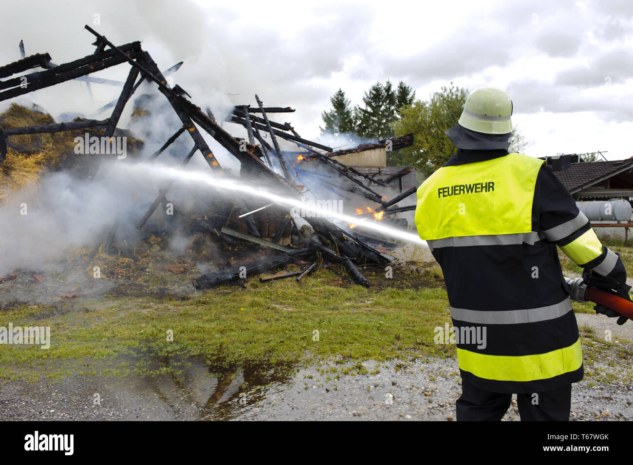 Feuerwehrmann im Einsatz bei brennenden Bauernhof in Deutschland Stockfoto