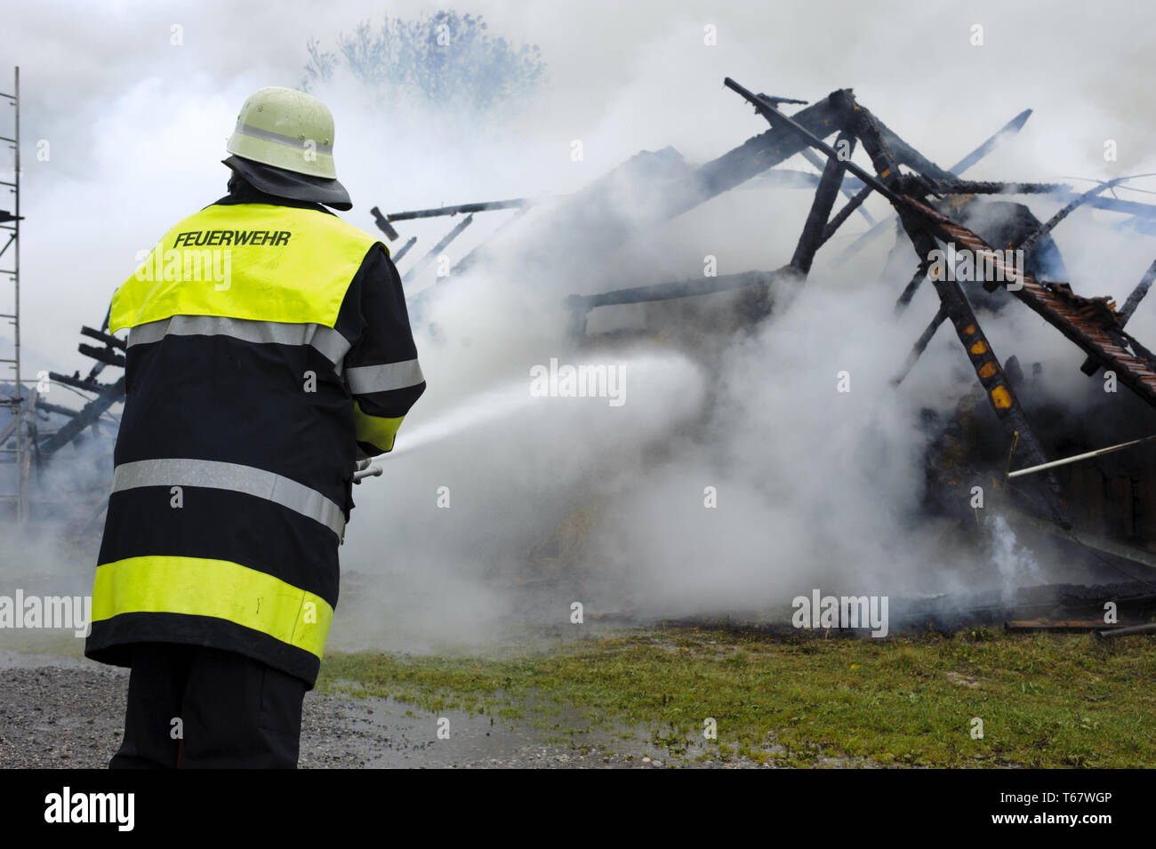 Feuerwehrmann im Einsatz bei brennenden Bauernhof in Deutschland Stockfoto