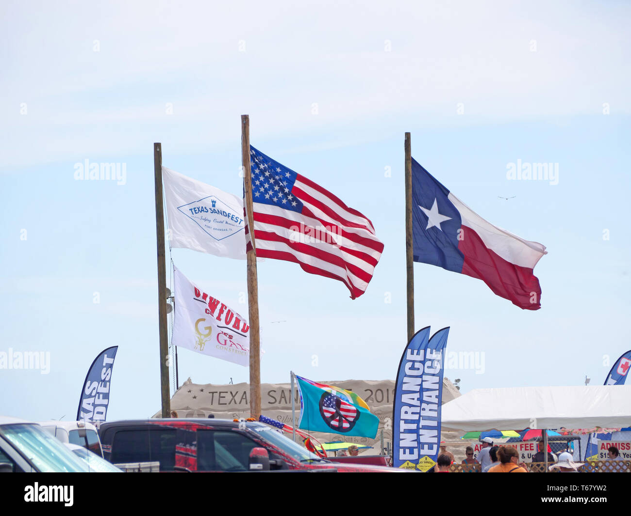 Texas Sandfest, United States und Texas State flags Fly gegen einen hellblauen Himmel am Eingang des 2019 Texas Sandfest in Port Aransas, Texas USA. Stockfoto