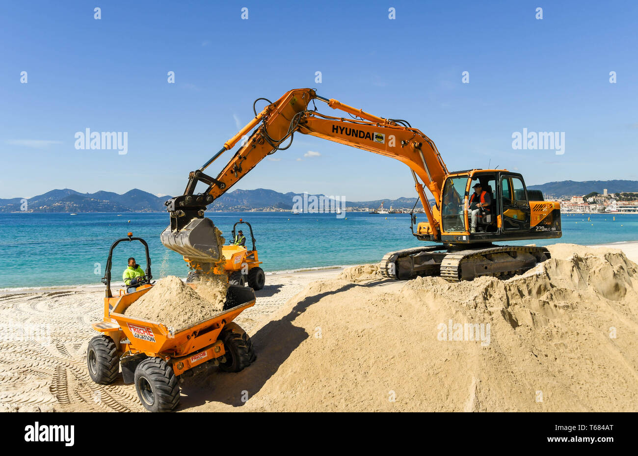 CANNES, Frankreich - April 2019: Der Schaufel von einem Bagger drop Sand in einen Kipper verwendet wird am Strand in Cannes zu verbessern. Stockfoto