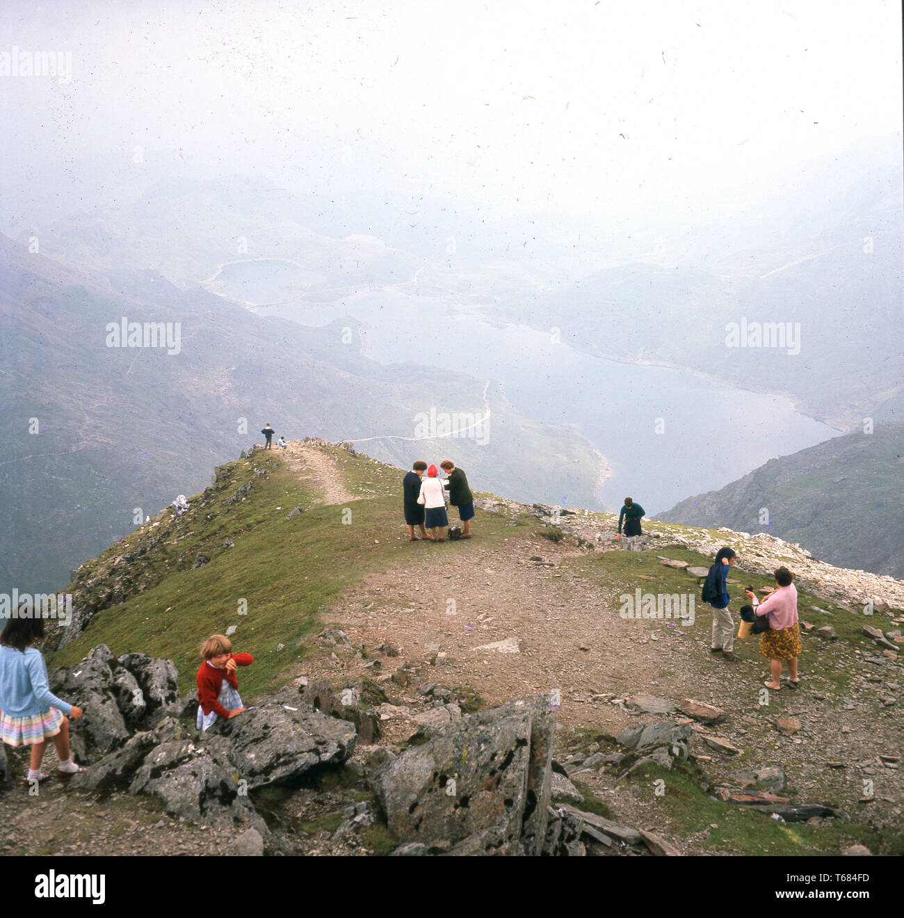 1960, historische, Erwachsene und Kinder auf dem Gipfel des Mount Snowdon, der höchste Berg in Wales. Sie sind alle normalen, alltäglichen Kleidung tragen, als wenn für einen Spaziergang im Park und nicht Spezialist Outdoor Gear, würde man erwarten, dass Sie heute zu tragen. Da der Snowdon ist der höchste Berg in Großbritannien (ohne Ben Nevis) und das Wetter könnte jeden Moment ändern, es zeigt, wie die Leute besucht wurden und Sehenswürdigkeiten Sehenswürdigkeiten in diesem Jahrzehnt später auf. Stockfoto