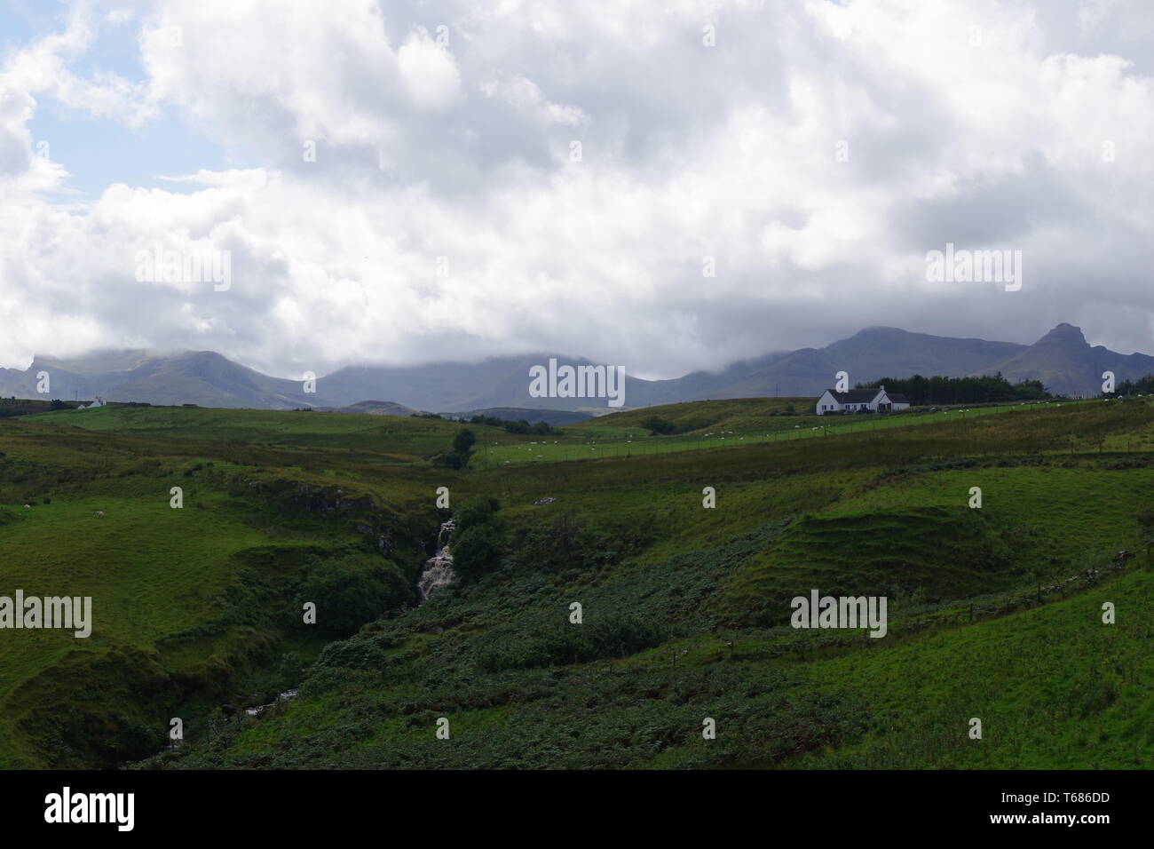 Lonfearn Brennen durch pulsierende grüne Landschaft unter niedrigen Cloud mit Berge bei Brüder Point (Rubha nam Brathairean) Isle of Skye, Schottland, Großbritannien. Stockfoto