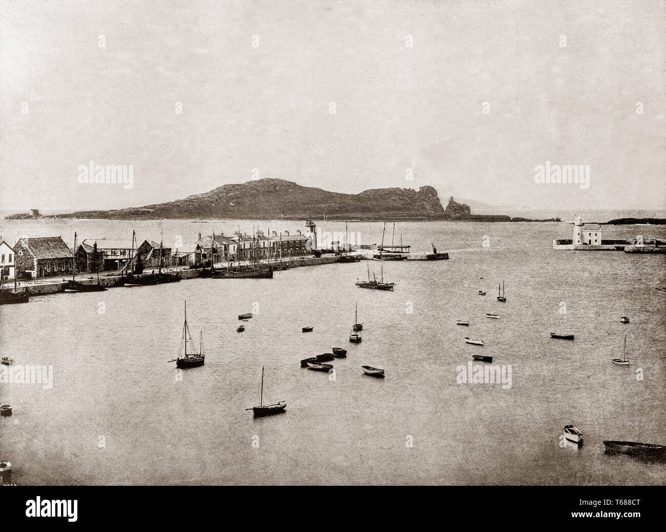 Jahrhundert Blick auf den Hafen von Howth, einem Fischerdorf und äußeren Vorort von Dublin, Irland. Ursprünglich nur ein kleines Fischerdorf, Howth mit seinen umliegenden einmal - Landkreis ist jetzt ein Vorort von Dublin, mit einer Mischung aus suburban Wohnentwicklung, wilden Hügel- und Heideflächen, Golfplätze, Cliff und Küstenwege, einem kleinen Steinbruch und eine Beschäftigte kommerzieller Fischereihafen. Stockfoto