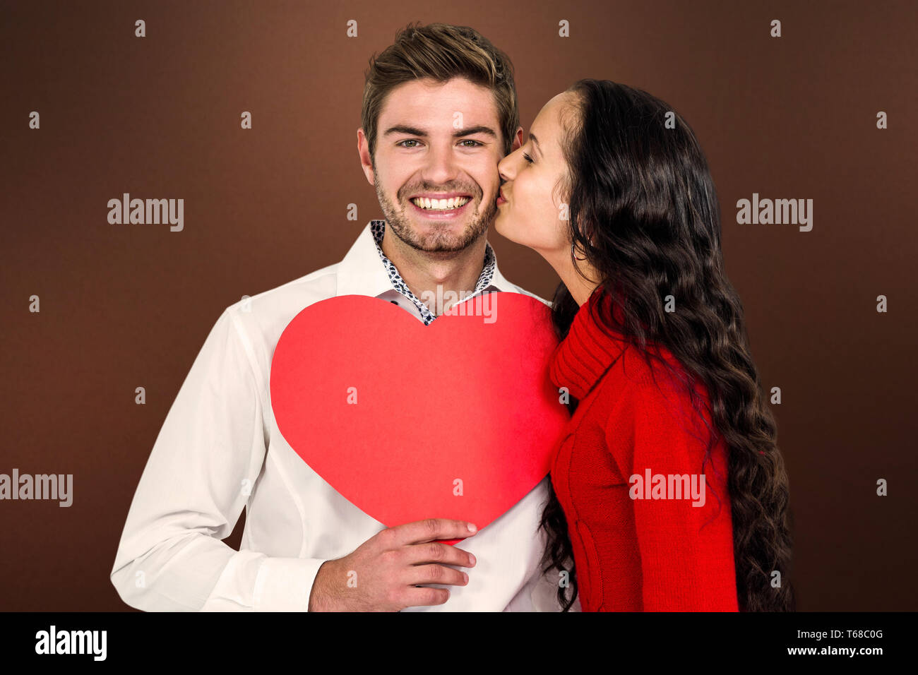 Zusammengesetztes Bild des Mannes halten Papierherz und wird von Freundin geküsst Stockfoto