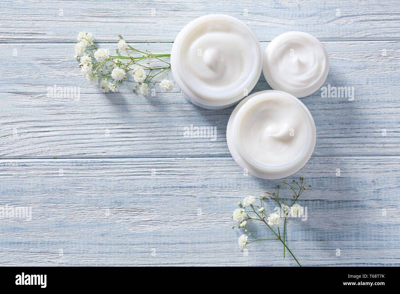 Gläser mit Hautpflege Kosmetik und Blumen auf Holz- Hintergrund Stockfoto