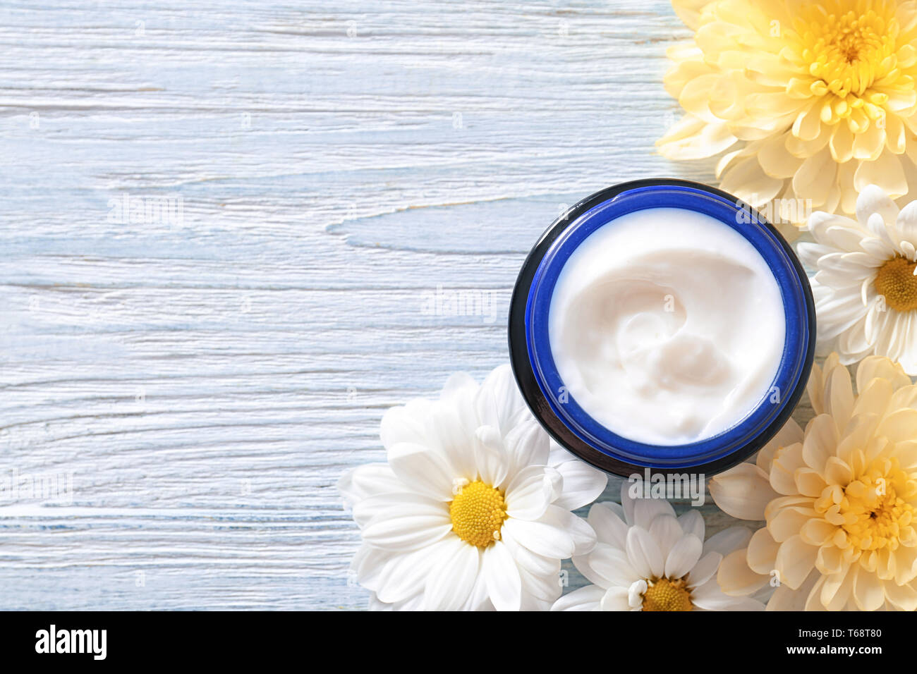 Jar mit Sahne und Blumen auf Holz- Hintergrund. Hautpflege Kosmetik Stockfoto