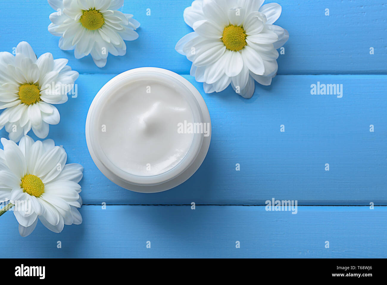 Jar von Körper Creme und wunderschöne Blumen auf farbigen Hintergrund Stockfoto