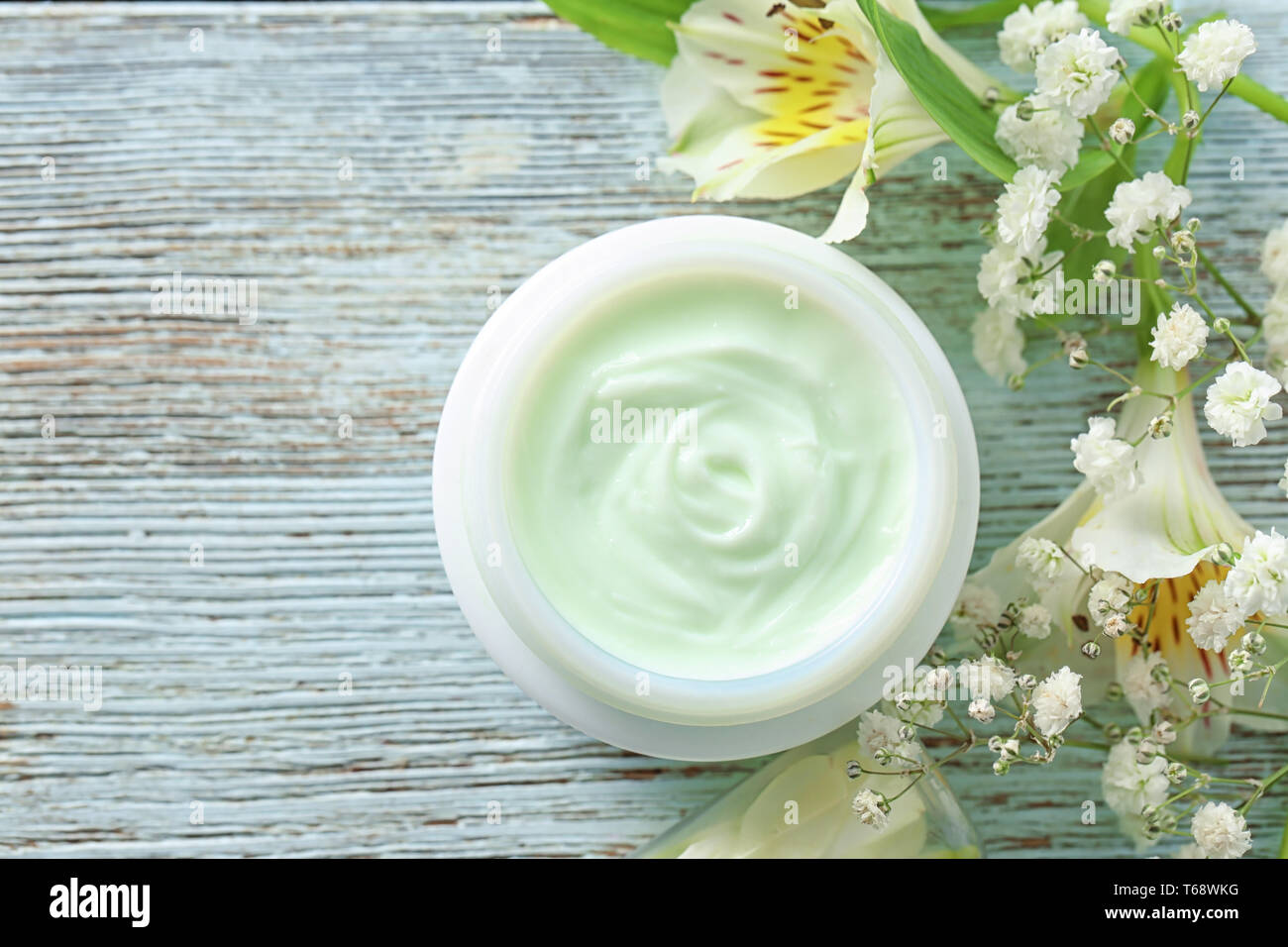 Jar von Körper Creme und wunderschöne Blumen auf Holz- Hintergrund Stockfoto