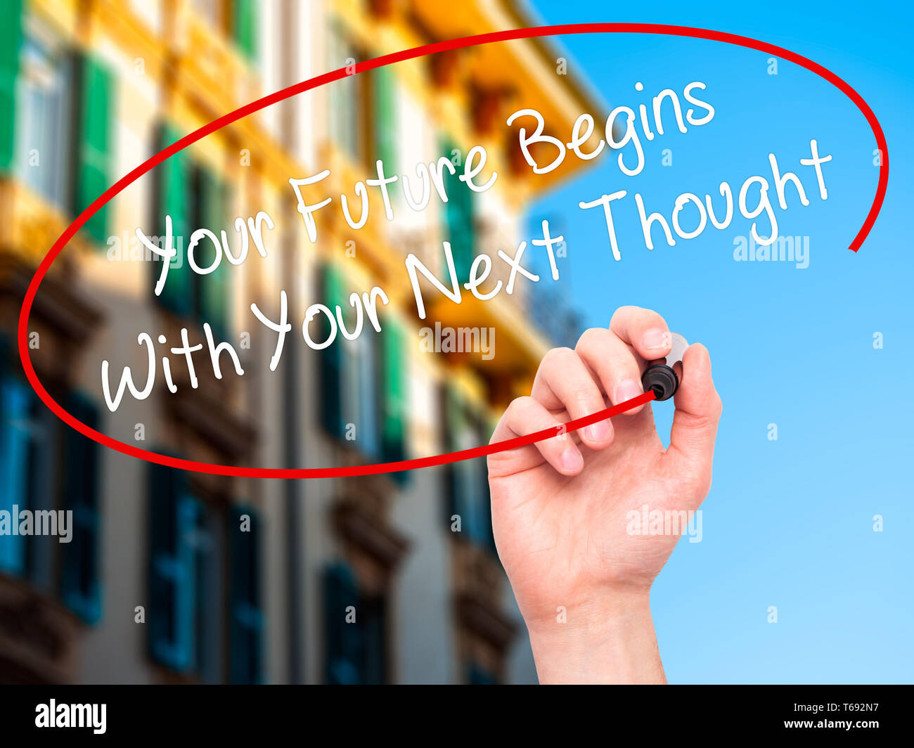 Mann Hand schreiben Ihre Zukunft beginnt mit Ihrer nächsten Gedanken mit schwarzem Marker auf visuelle Bildschirm. Stockfoto