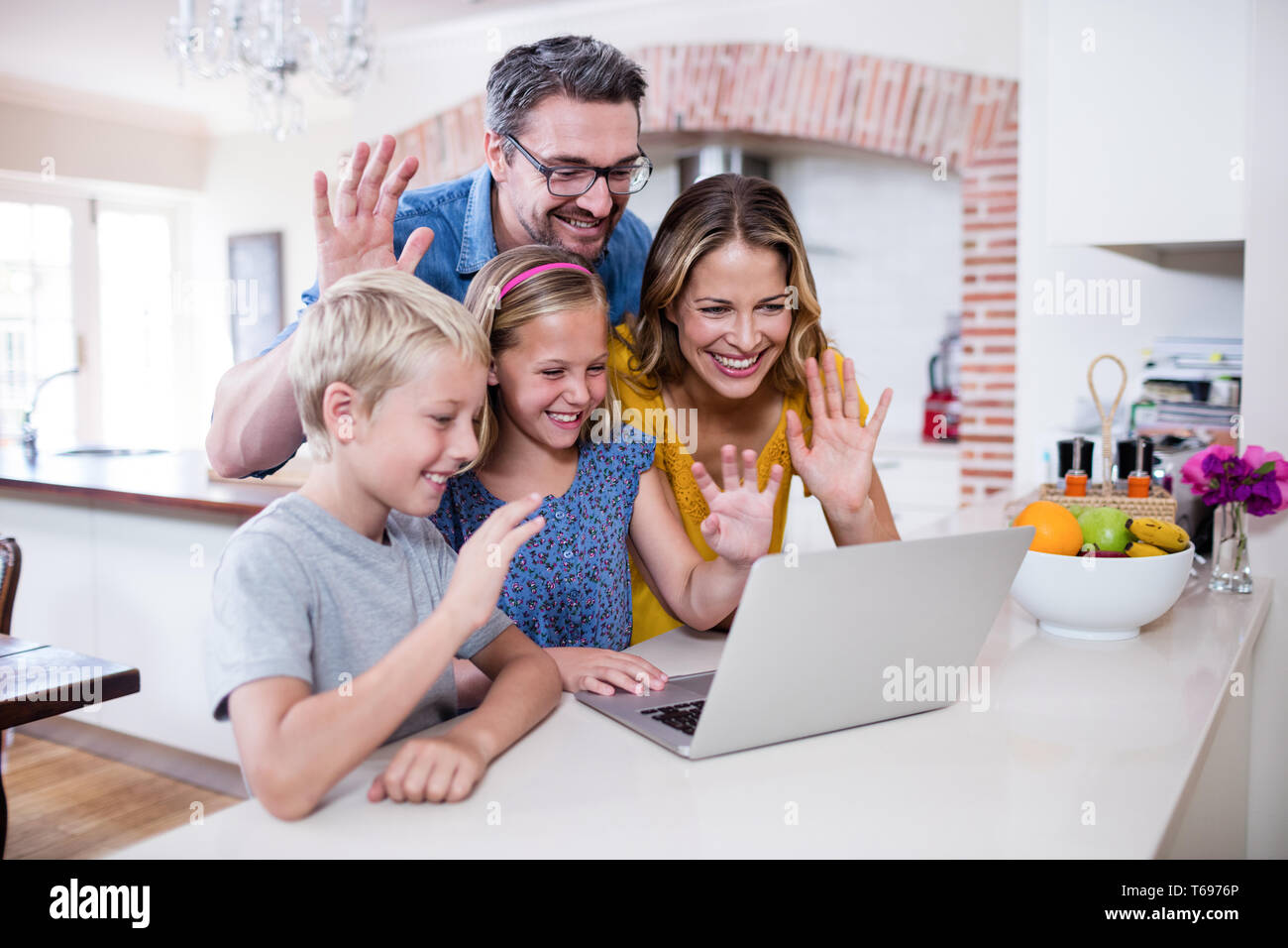 Eltern und Kinder winken Hände während mit Laptop für video-chat Stockfoto