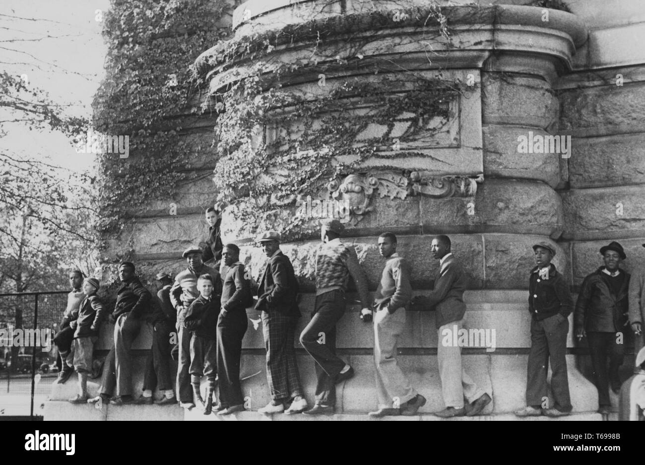 Schwarz-weiß Foto, von einer Reihe von Männern und Jungen, Balancieren auf einem Felsvorsprung des Giessens rund um die Basis der MacDonough Halle an der US Naval Academy in Annapolis, Maryland, USA; von John vachon fotografiert, unter der Schirmherrschaft von Farm Security Administration der Vereinigten Staaten, 1940. Von der New York Public Library. () Stockfoto