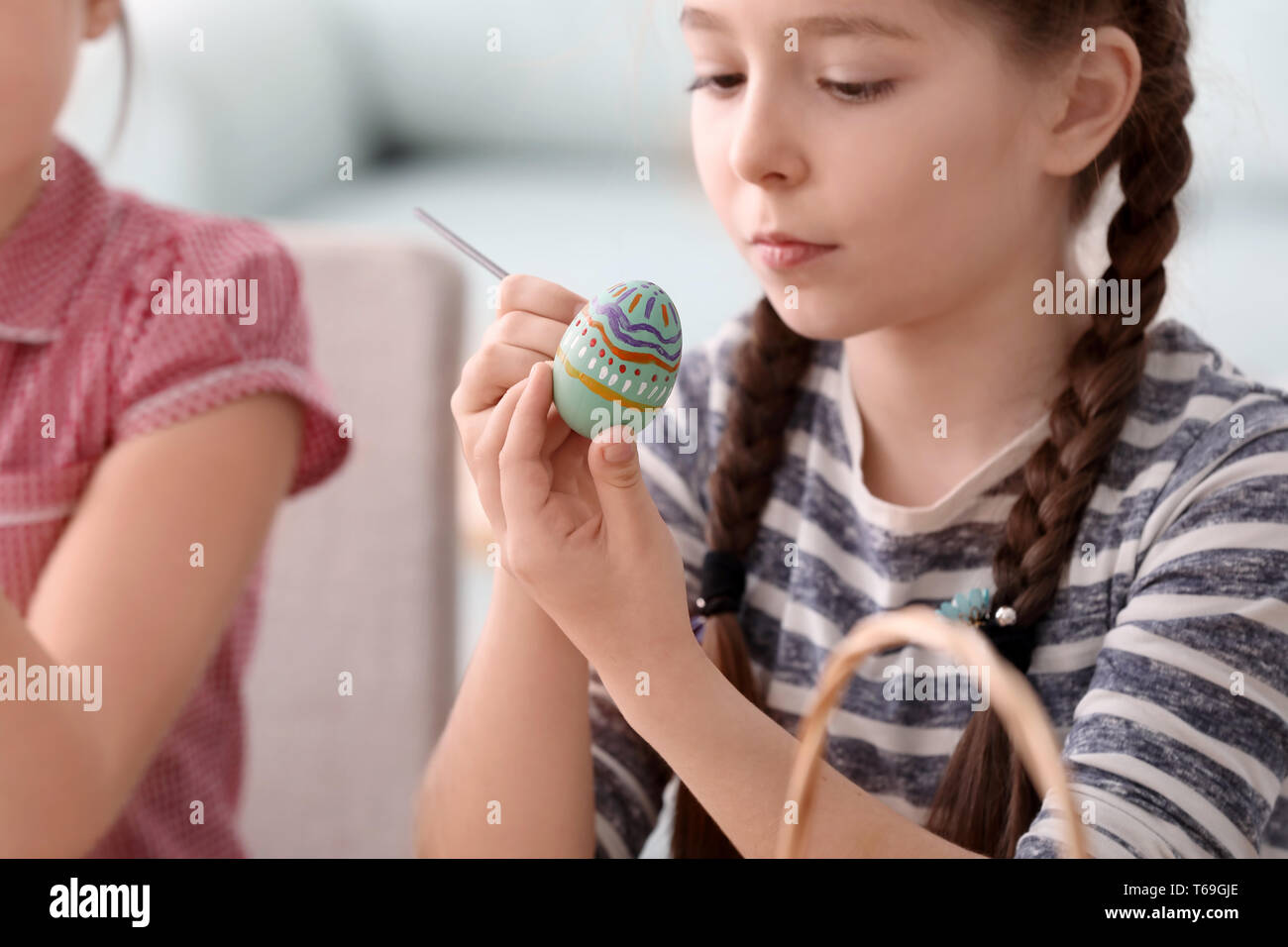 Süße kleine Mädchen malen Eier zu Ostern zu Hause Stockfoto