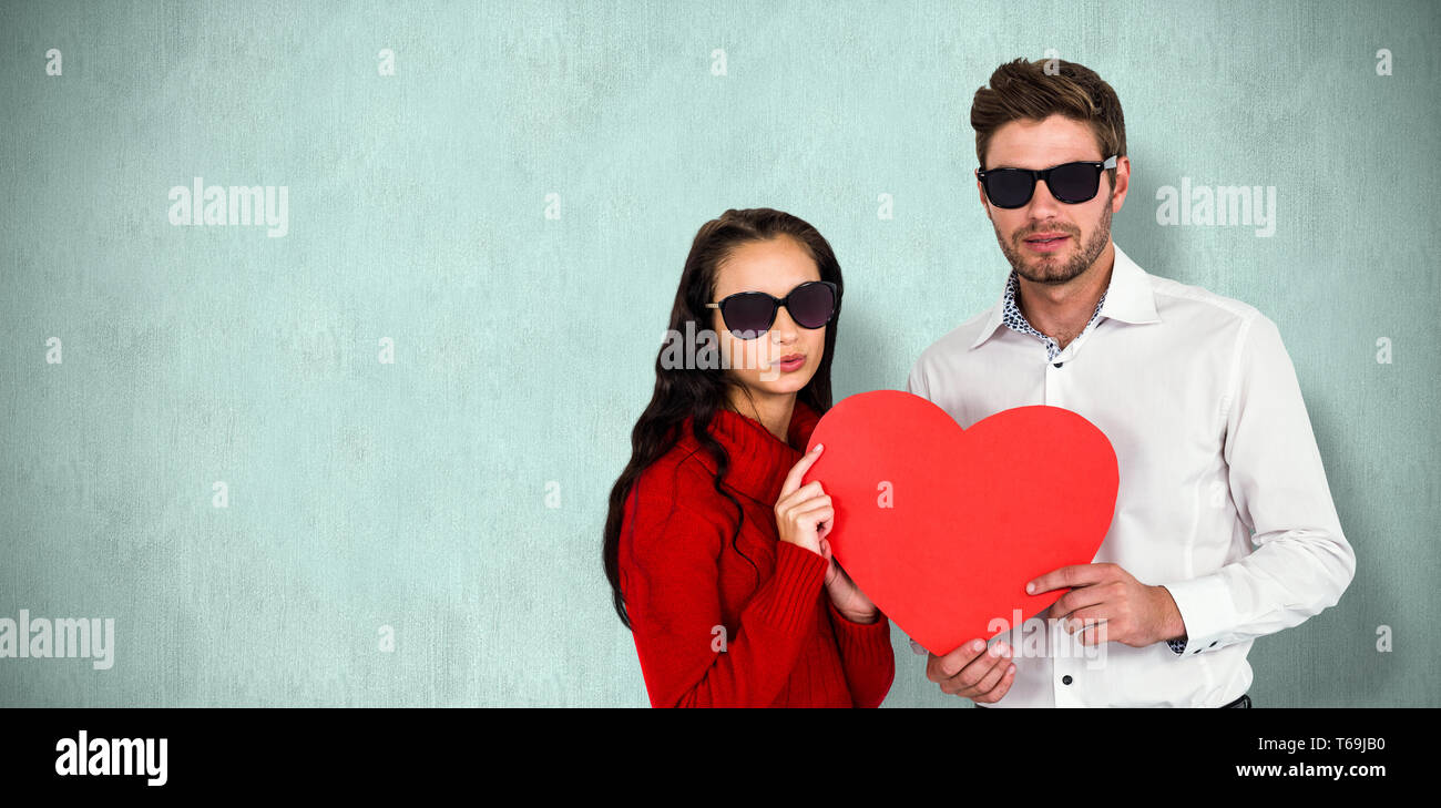 Zusammengesetztes Bild Porträt des Paares mit Sonnenbrille hält Papierherz Stockfoto