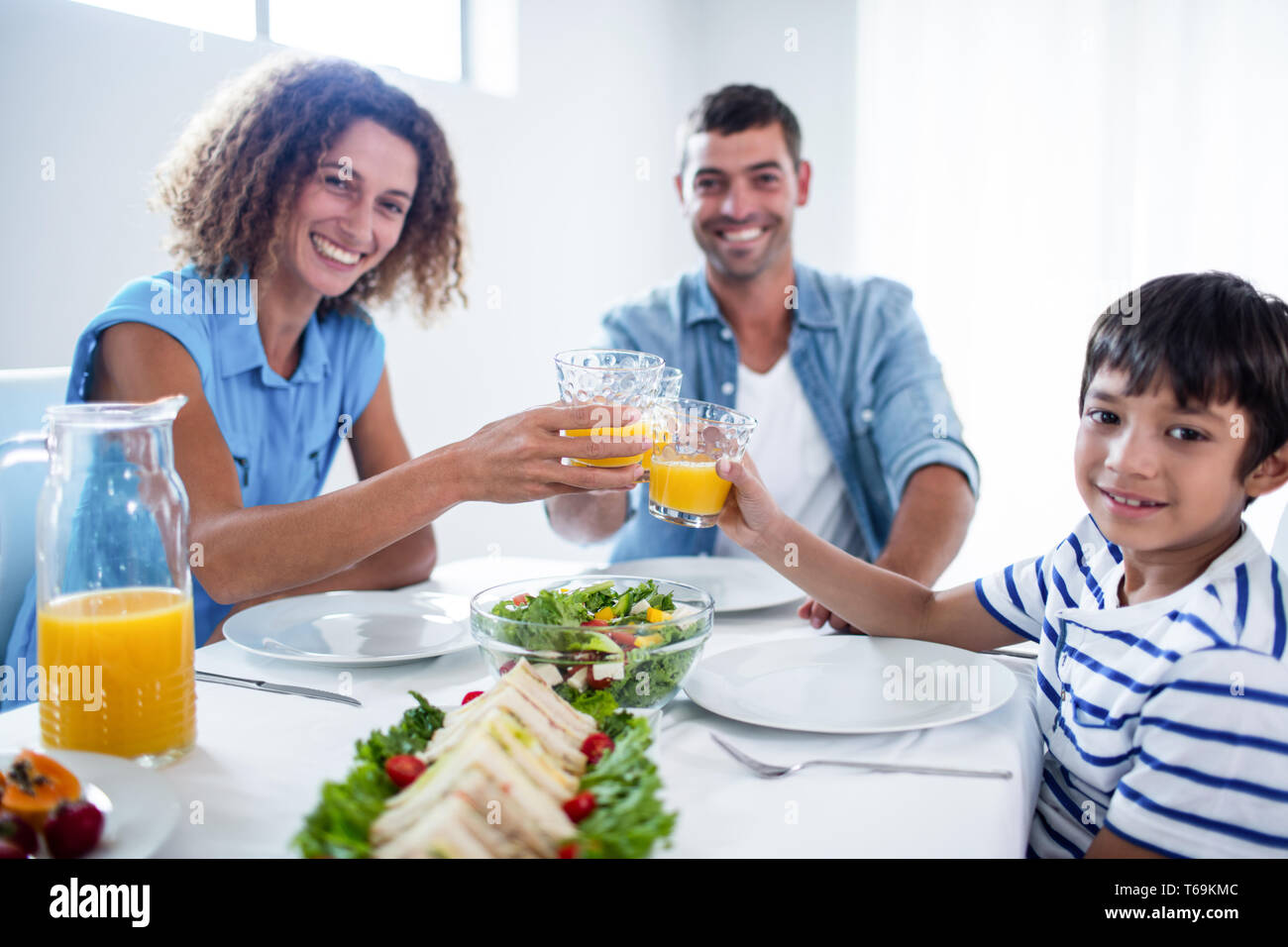 Porträt der Familie Toasten Gläser Orangensaft beim Frühstück Stockfoto