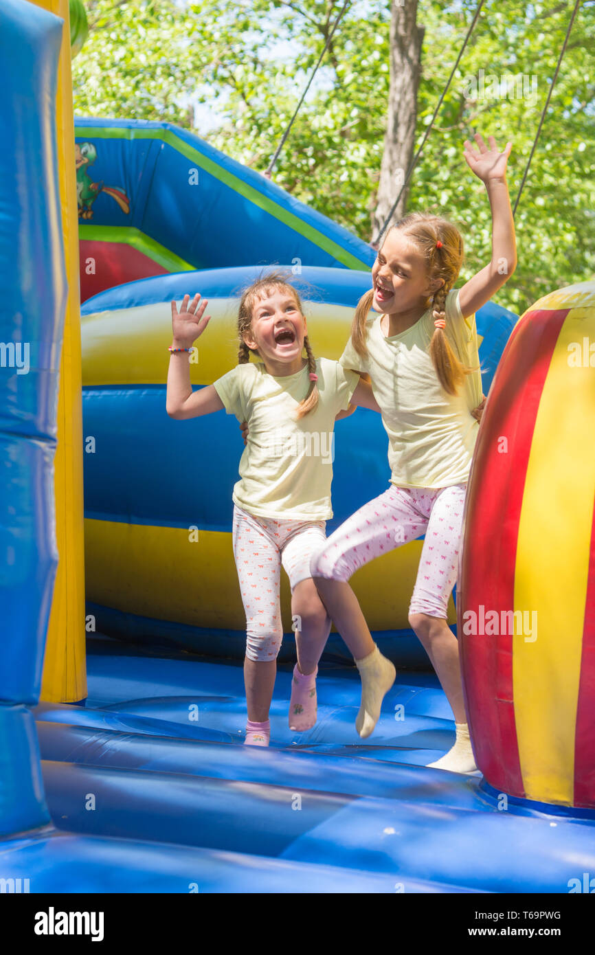 Zwei Mädchen verzog das Gesicht glücklich auf einem aufblasbaren Trampolin springen Stockfoto