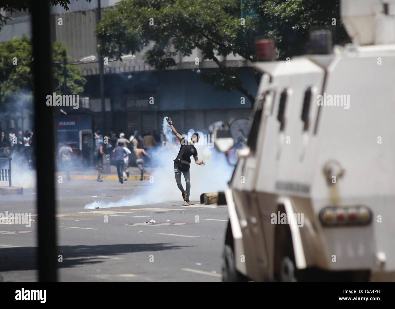 Caracas, Venezuela. 30 Apr, 2019. Ein Demonstrator wirft ein tränengas Granate gegen Sicherheitskräfte in Auseinandersetzungen in der Hauptstadt. Nach dem Aufstand einiger Soldaten gegen die Regierung Venezuelas Präsident Maduro, Demonstranten und Regierung - loyale Sicherheitskräfte in der Hauptstadt Caracas haben hart gekämpft. Credit: Rafael Hernandez/dpa/Alamy leben Nachrichten Stockfoto