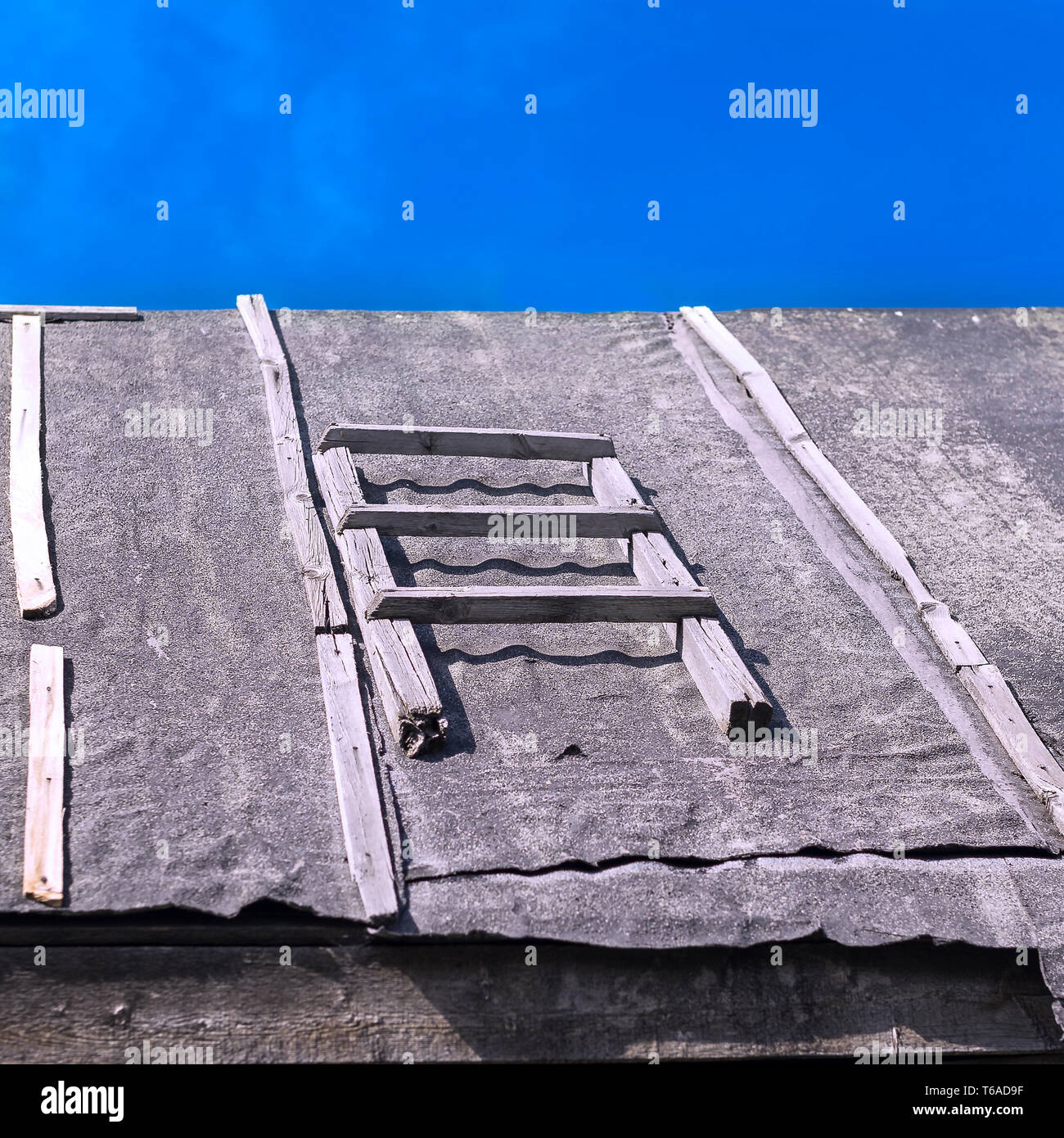 Abschnitt einer Holzleiter auf einem Stalldach bedeckt mit Abdichtung Teerpappe gegen Sommer blauer Himmel. Dacharbeiten Reparaturen, Bau Konzept Stockfoto