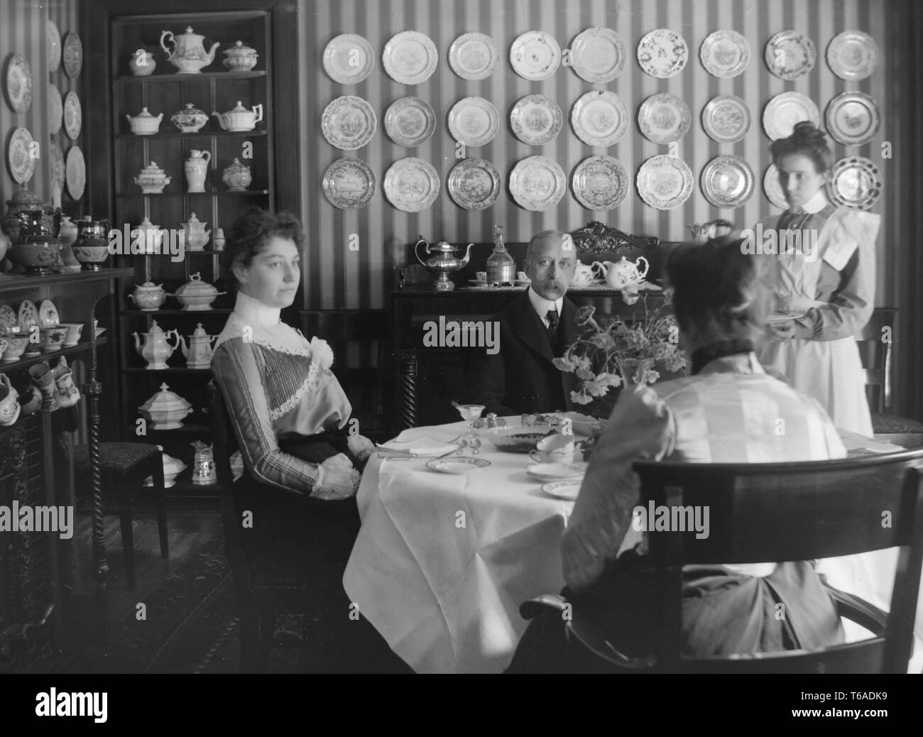 Ein Dienstmädchen serviert Abendessen zu einem wohlhabenden viktorianischen Familie, Ca. 1900. Stockfoto
