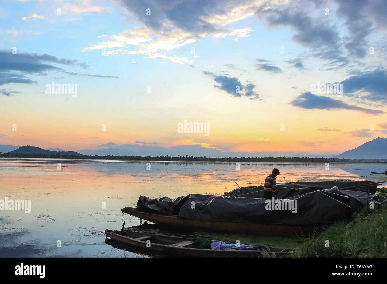 Einen wunderschönen Sonnenuntergang auf dem Dal Lake in Kaschmir. Boote der Fischer geparkt am Ufer des Sees Stockfoto