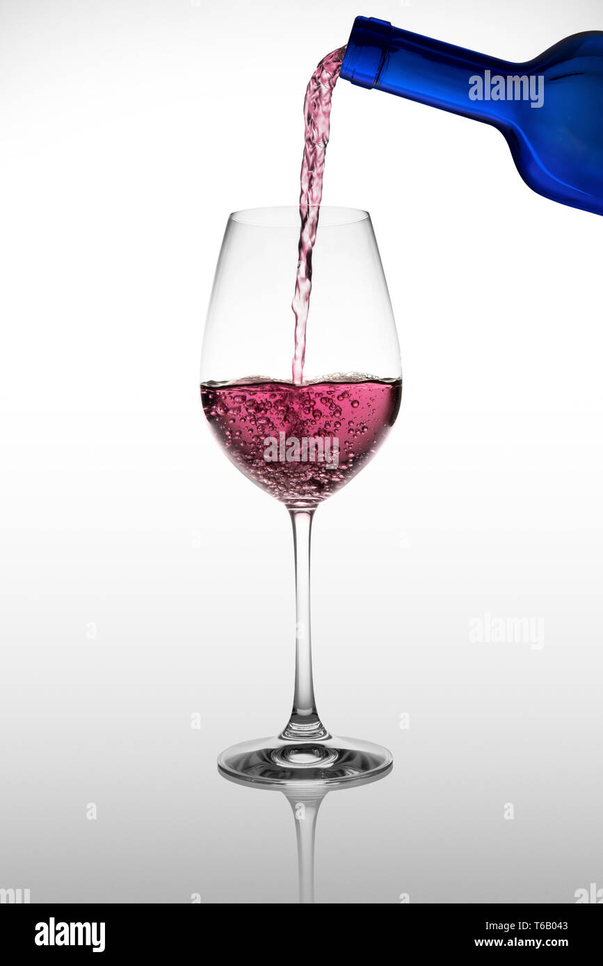 Wein Glas mit rotem Wein gießen es mit Reflektion Stockfoto