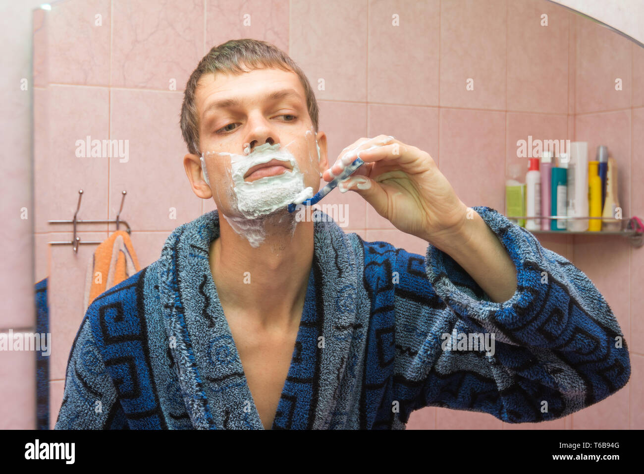 Junger Mann rasiert Hals vor dem Spiegel Stockfoto