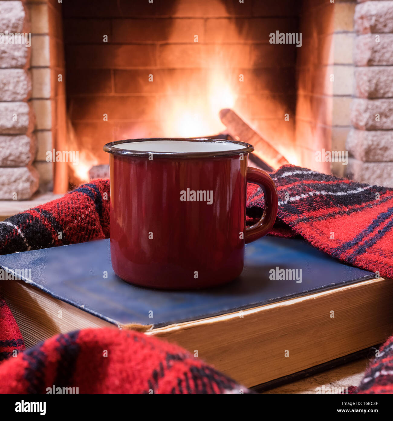 Becher mit heißem Tee, Wolle Schal und buchen Sie in der Nähe der gemütlichen Kamin, im Landhaus, Winter Urlaub. Stockfoto