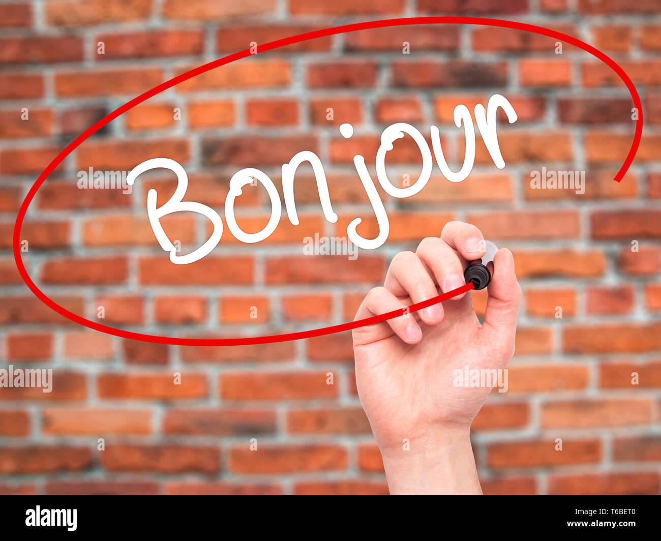 Mann Hand schreiben Bonjour (Guten Morgen in französischer Sprache) mit schwarzem Marker auf visuelle Bildschirm Stockfoto