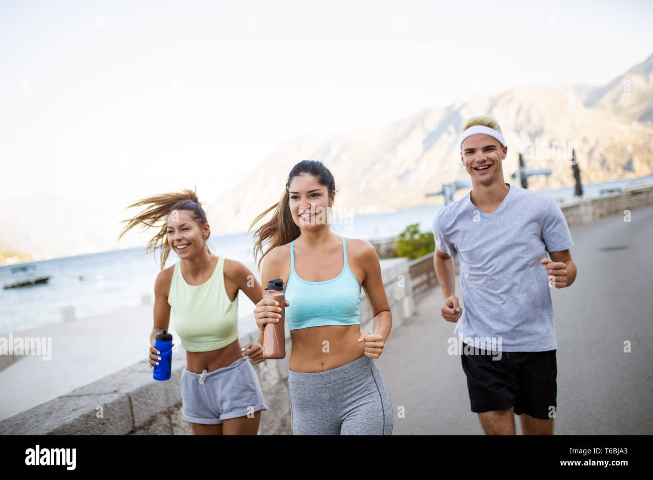 Glückliche Menschen Joggen im Freien. Laufen, Sport, Bewegung und gesunde Lebensweise Konzept Stockfoto