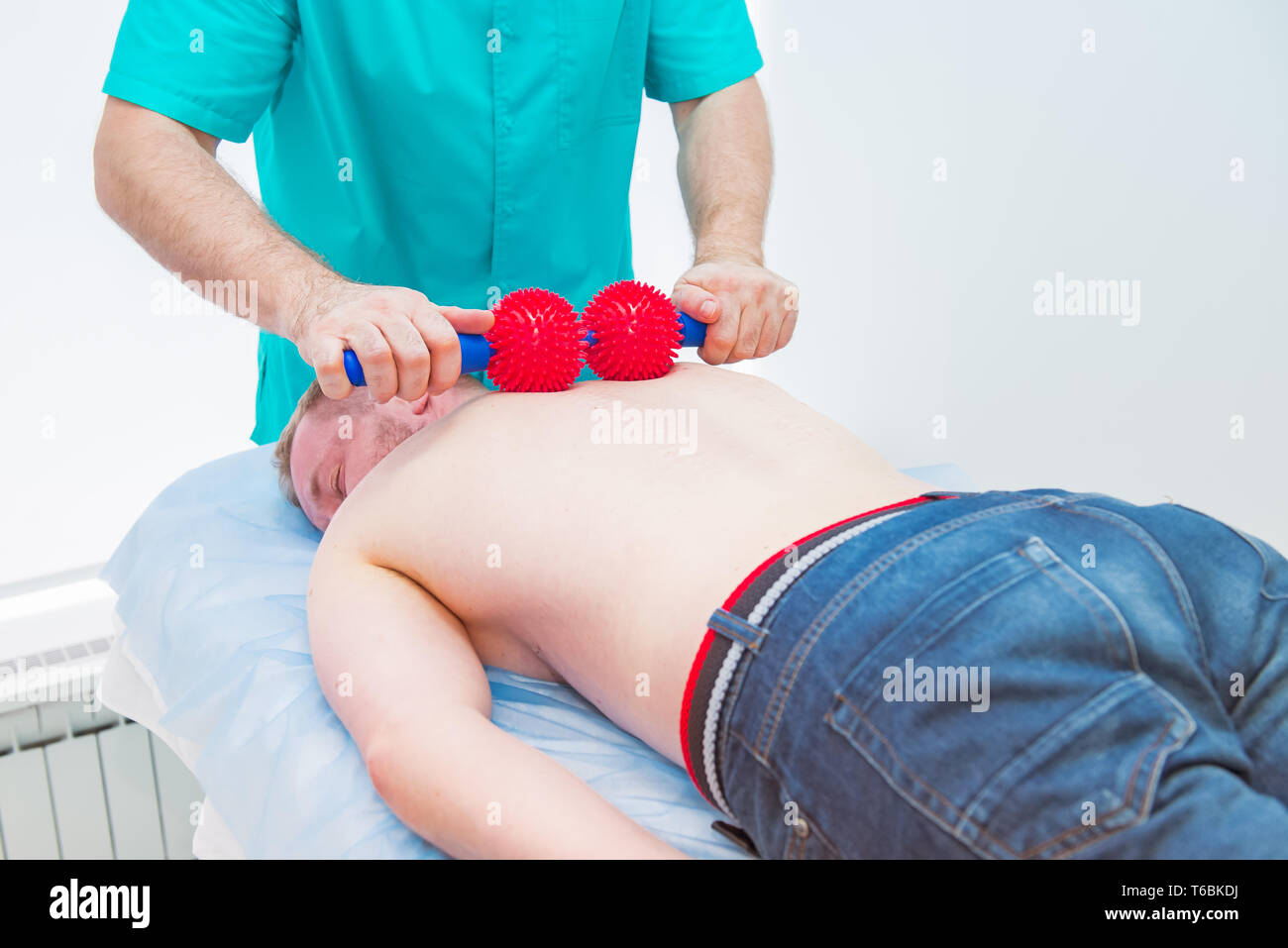 Junge Mann an der Physiotherapie, die Kugel Massage Therapeuten. Ein chiropraktor behandelt Brustwirbelsäule der Patienten und der medizinischen Büro. Neurologie, Ost Stockfoto