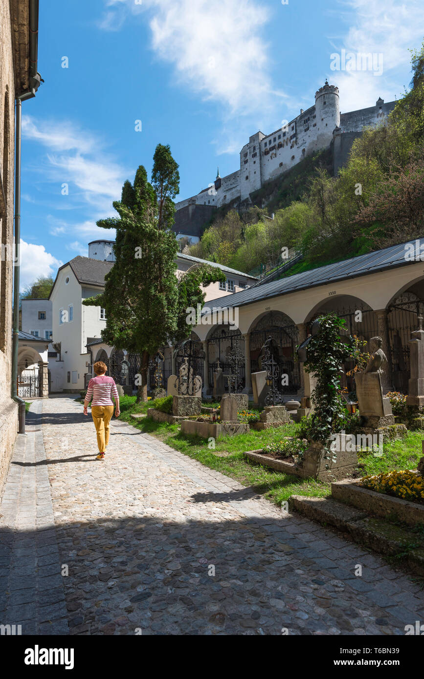 Petersfriedhof Friedhof, Ansicht der Rückseite eine Frau mittleren Alters zu Fuß durch die petersfriedhof Friedhof in der Altstadt (Altstadt) Quartal Salzburg. Stockfoto