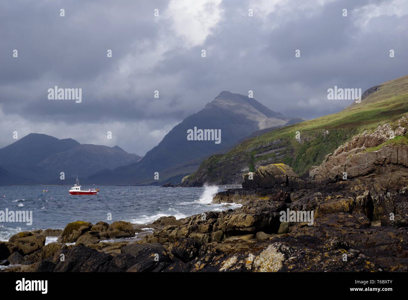 Kleine rote Fischerboot auf dem Loch Scavaig, dominiert von der Cullin Mountains auf einem Stimmungsvollen Herbsttag. Elgol, Isle of Skye, Schottland, Großbritannien. Stockfoto