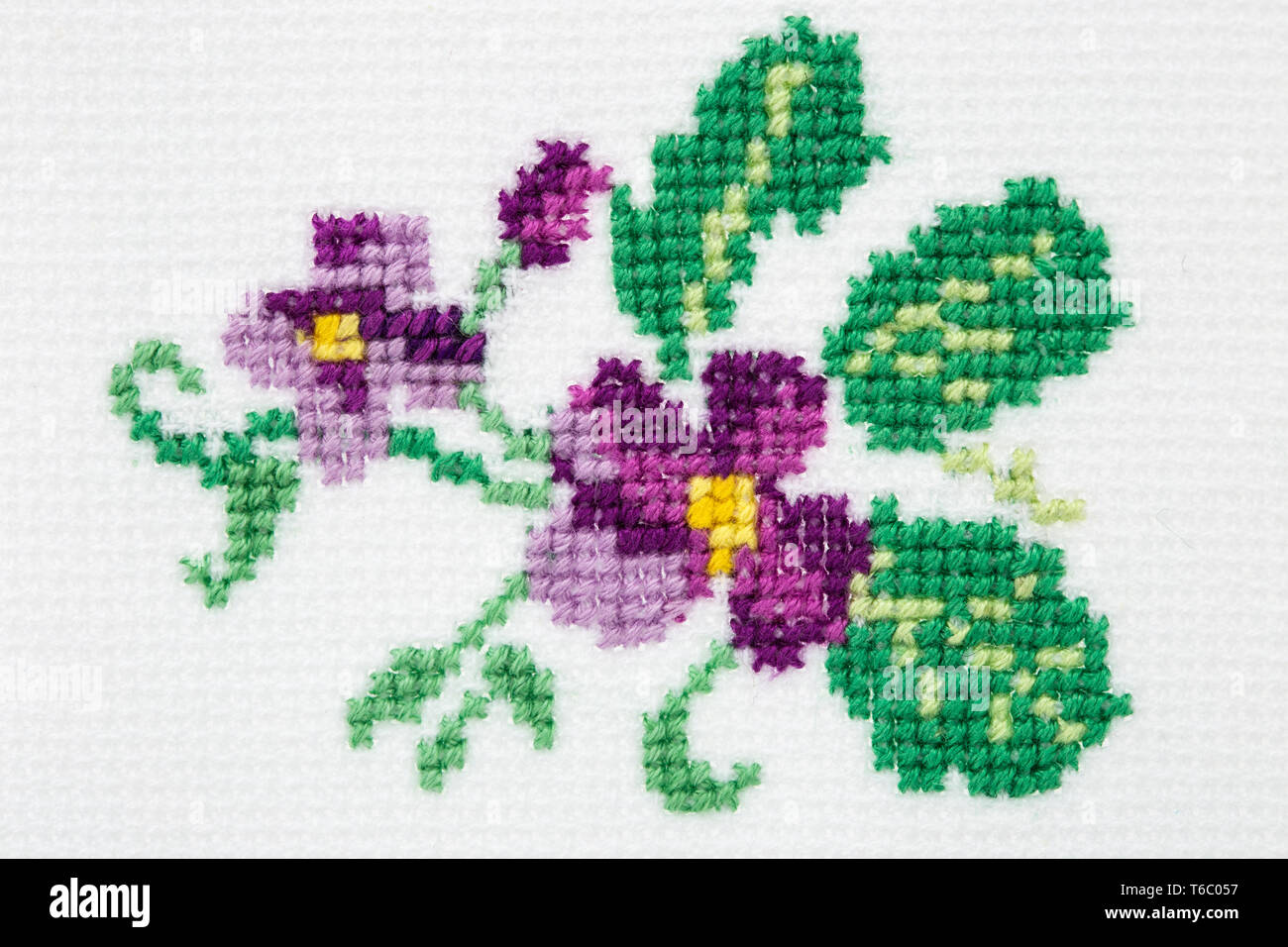 Violette Blume bestickt mit einem Kreuz auf textile Leinwand Stockfoto