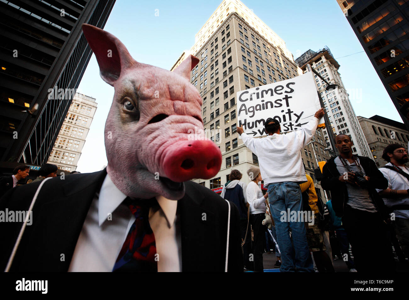 Die Demonstranten aus der Besetzt die Wall Street in der zucotti Park gegen Gier und Ungleichheit demonstrieren. Der Ire ist besonders auf die Welt der Finanzen konzentriert. Ein Mann in ein Schwein Maske in den Vordergrund. Stockfoto