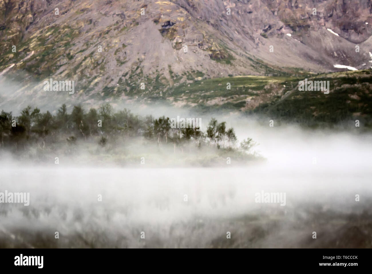 Standard der Schönheit der Natur. Bergsee zwischen Hügeln am frühen Morgen Nebel. Nordic Region. Verschwommen Stockfoto