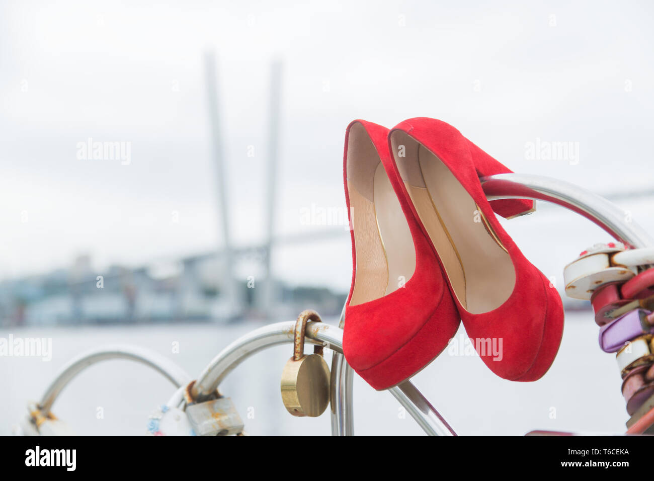 Rot luxus Schuhe hängt am Zaun mit Schlössern der Herzen gegen den Himmel Stockfoto
