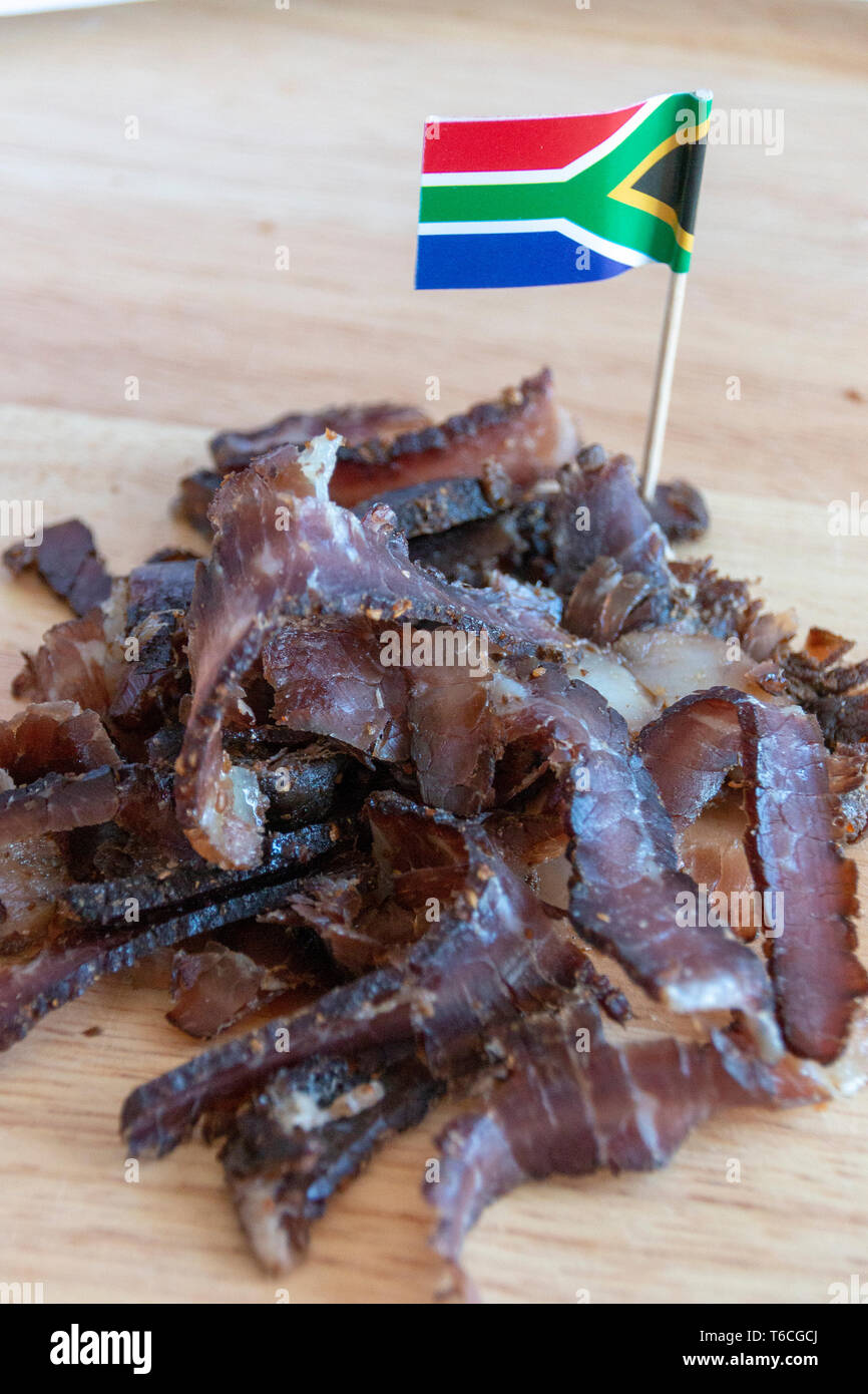 Eine Nahaufnahme von einem Stapel der Südafrikanische biltong auf einem Holz Schneidebrett mit einem kleinen südafrikanischen Flagge auf der Seite Stockfoto