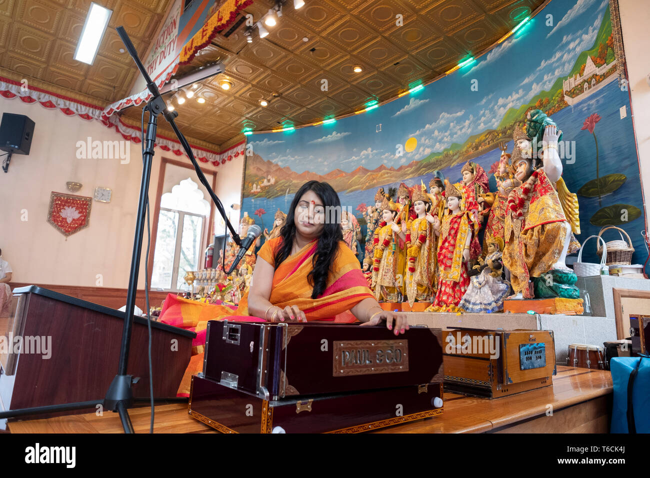 PANDITA. Eine weibliche Hindu Priesterin singt ein Gebet während der Wiedergabe eines Harmonium an einem Tempel in Jamaica, Queens, New York City. Stockfoto