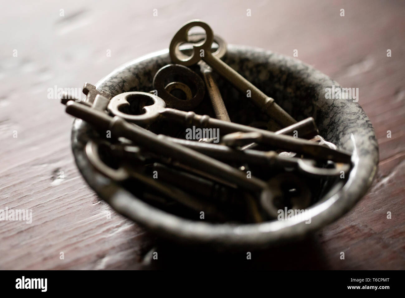 Eine kleine Emaille Schüssel mit antiken Tasten sitzen auf einem kirschholz Tisch gefüllt. Stockfoto