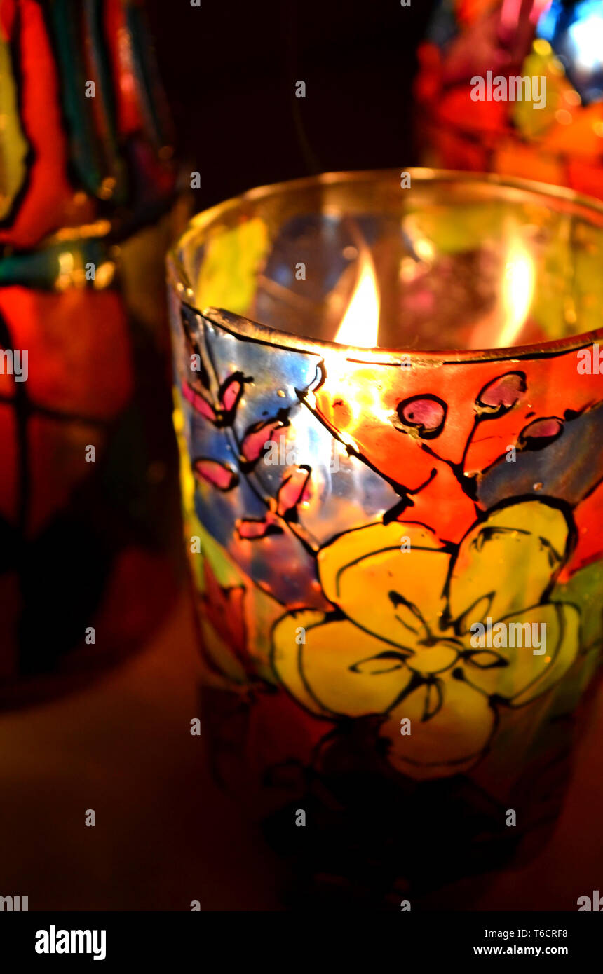 Glas Kerzenhalter bemalten Glasfenster Lacke mit einer brennenden Kerze im Inneren Stockfoto