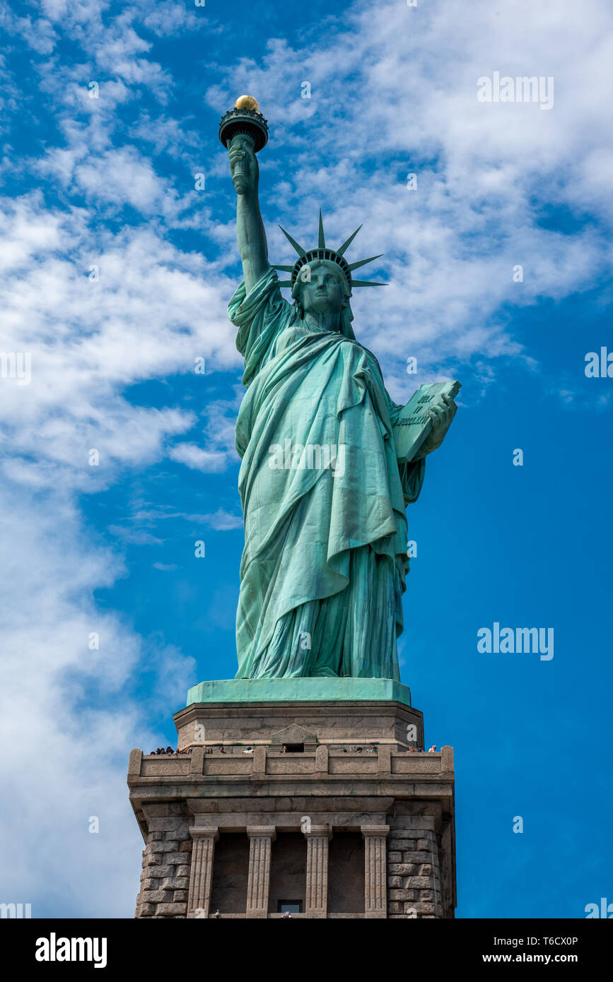 Schuss der Freiheitsstatue in New York City, USA. Der Schuß wird während ein schöner sonniger Tag mit blauem Himmel und weißen Wolken im Hintergrund Stockfoto