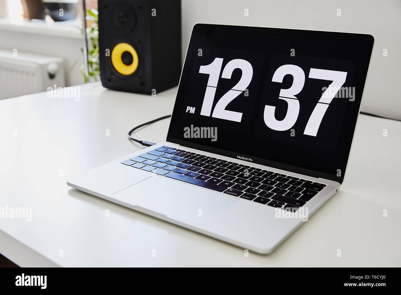Apple MacBook Pro Notebook mit der Uhr als Bildschirmschoner auf dem großen  weißen Ikea Schreibtisch Büro mit dem schwarz gelb Lautsprecher, iPhone im  Hintergrund Stockfotografie - Alamy