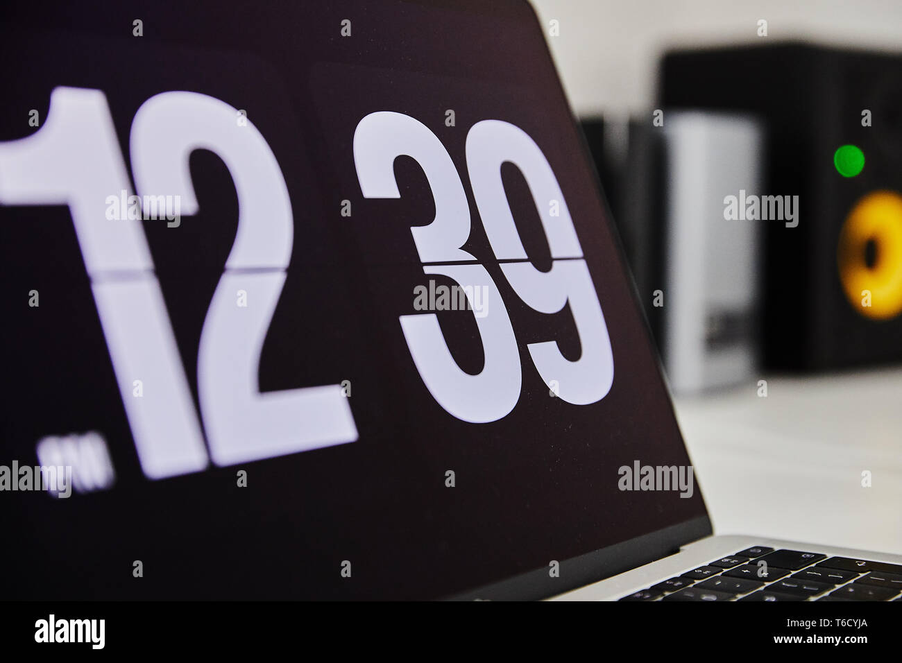 Apple MacBook Pro Notebook mit der Uhr als Bildschirmschoner auf dem großen  weißen Ikea Schreibtisch Büro mit dem schwarz gelb Lautsprecher, iPhone im  Hintergrund Stockfotografie - Alamy