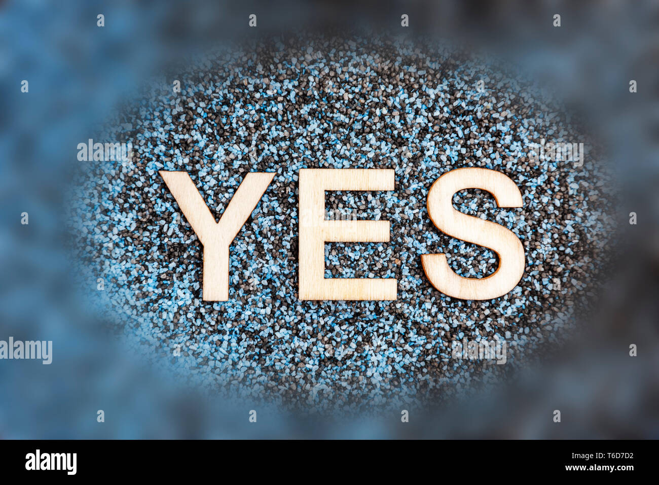 Gemischt schwarz und Blau dekorative Sand nach außen Oval in die Weichheit mit dem Wort JA aus der angewandten Holz Buchstaben. Stockfoto