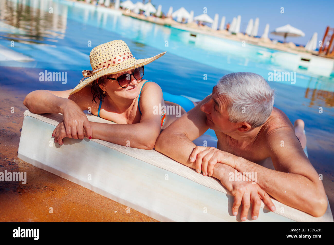 Senior paar Relaxen im Pool liegen auf eine Chaiselongue. Leute genießen Sommer Urlaub. Stockfoto Senior paar Relaxen im Pool liegen auf eine Chaiselongue. Leute genießen Sommer Urlaub. Stockfoto